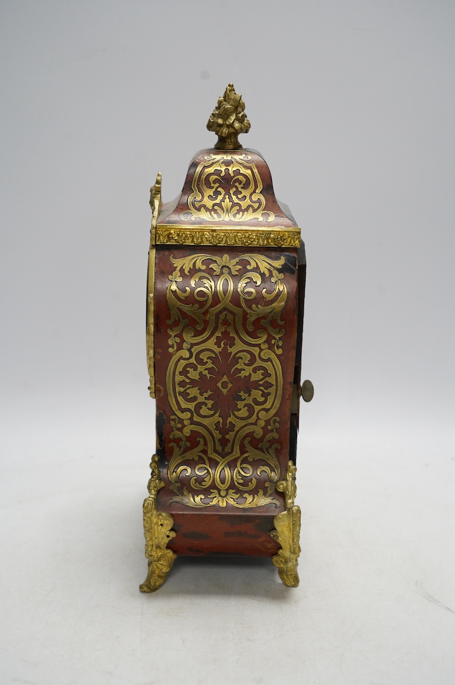 A Louis XV style red boulle eight day mantel clock, with bracket and pendulum, clock 30cm high. Condition - fair, not tested